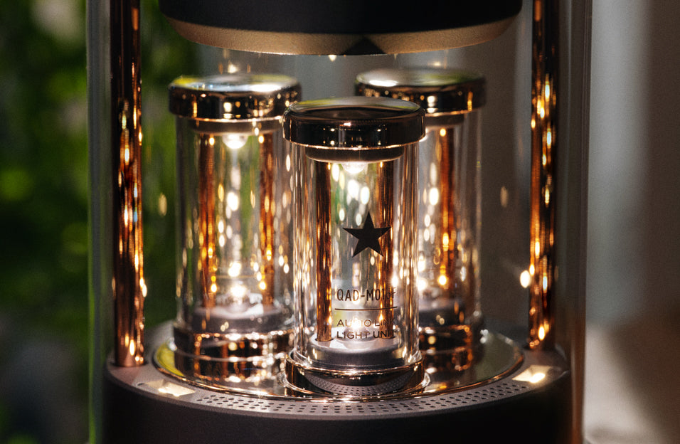 Close-up of the illuminated light tubes inside BALMUDA The Speaker, with reflective glass and metallic components.
