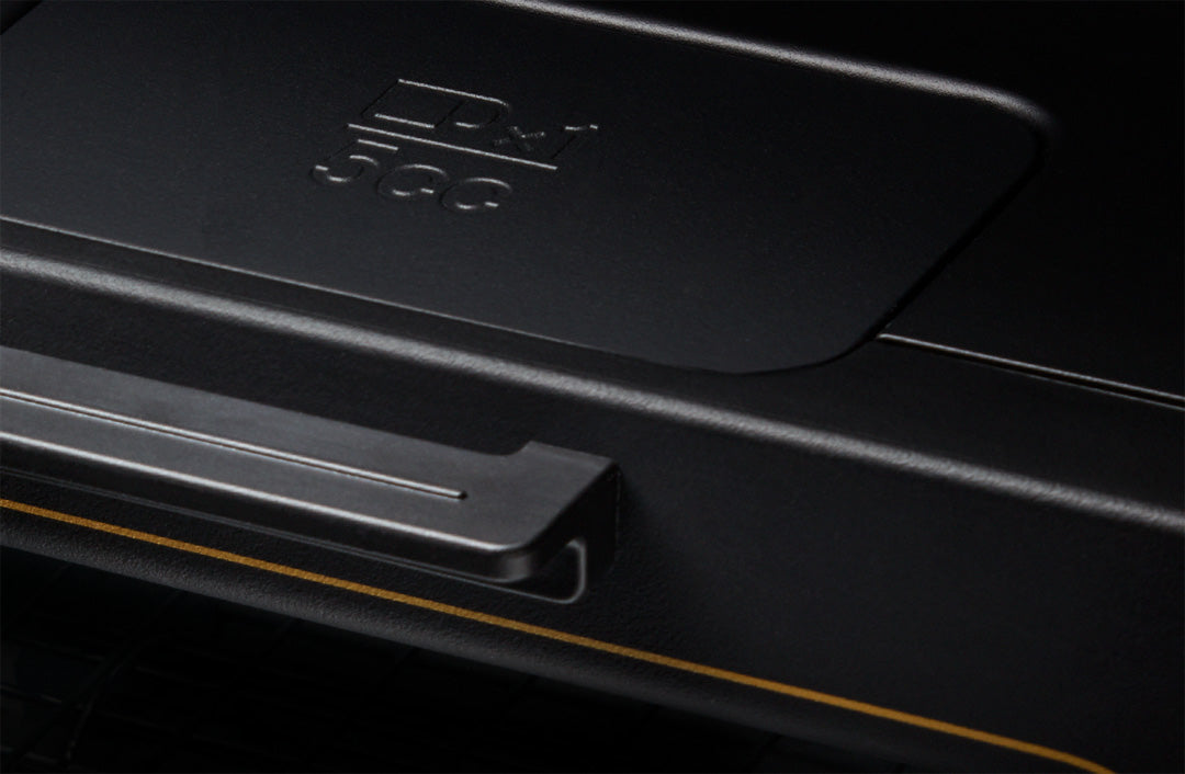 Close-up of a black toaster oven's front panel, highlighting the handle and a small rectangular section with an embossed '5cc' marking. The design features a matte black finish with subtle gold trim, giving it a modern and minimalistic aesthetic.