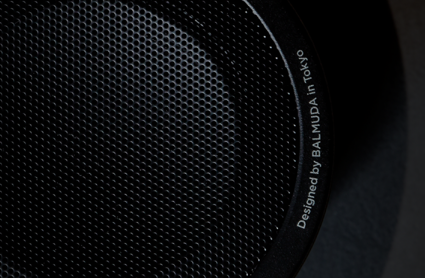 Close-up of the speaker grill with the words 'Designed by BALMUDA in Tokyo' etched along the rim.