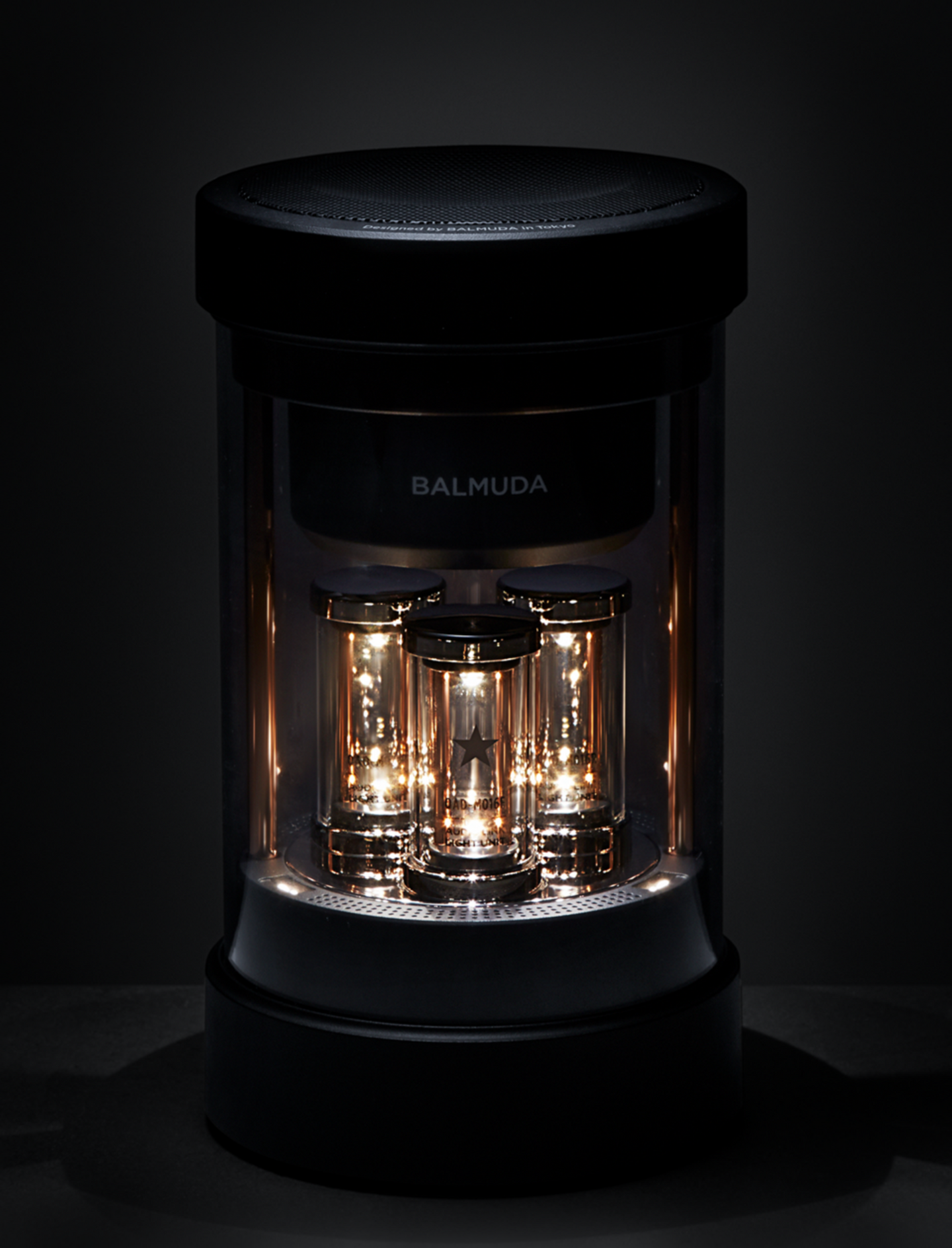BALMUDA The Speaker glowing softly in a dark environment, showing the internal light tubes.
