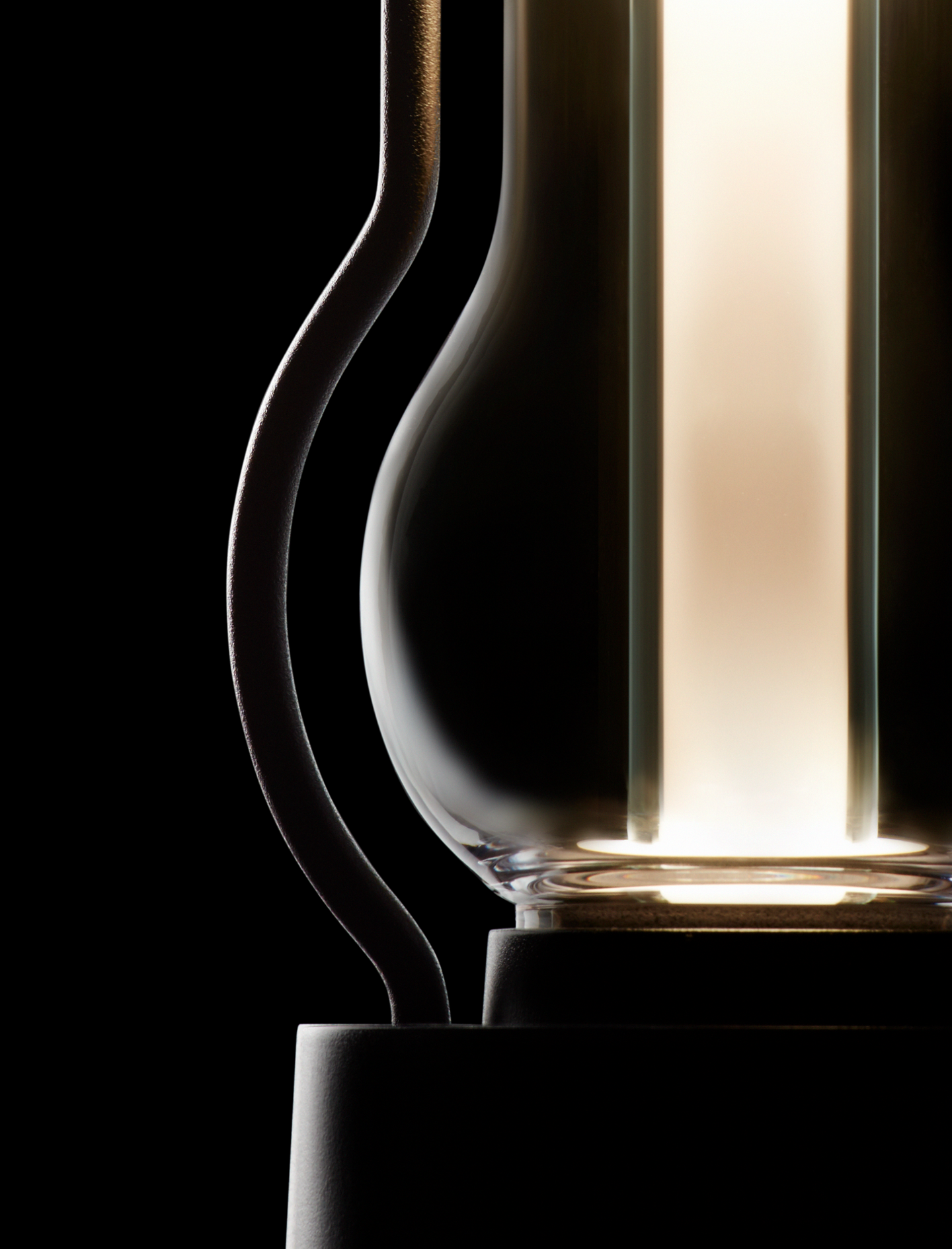 Close-up of BALMUDA The Lantern’s illuminated chamber, highlighting the elegant curve of the frame and the soft glow of the light inside.