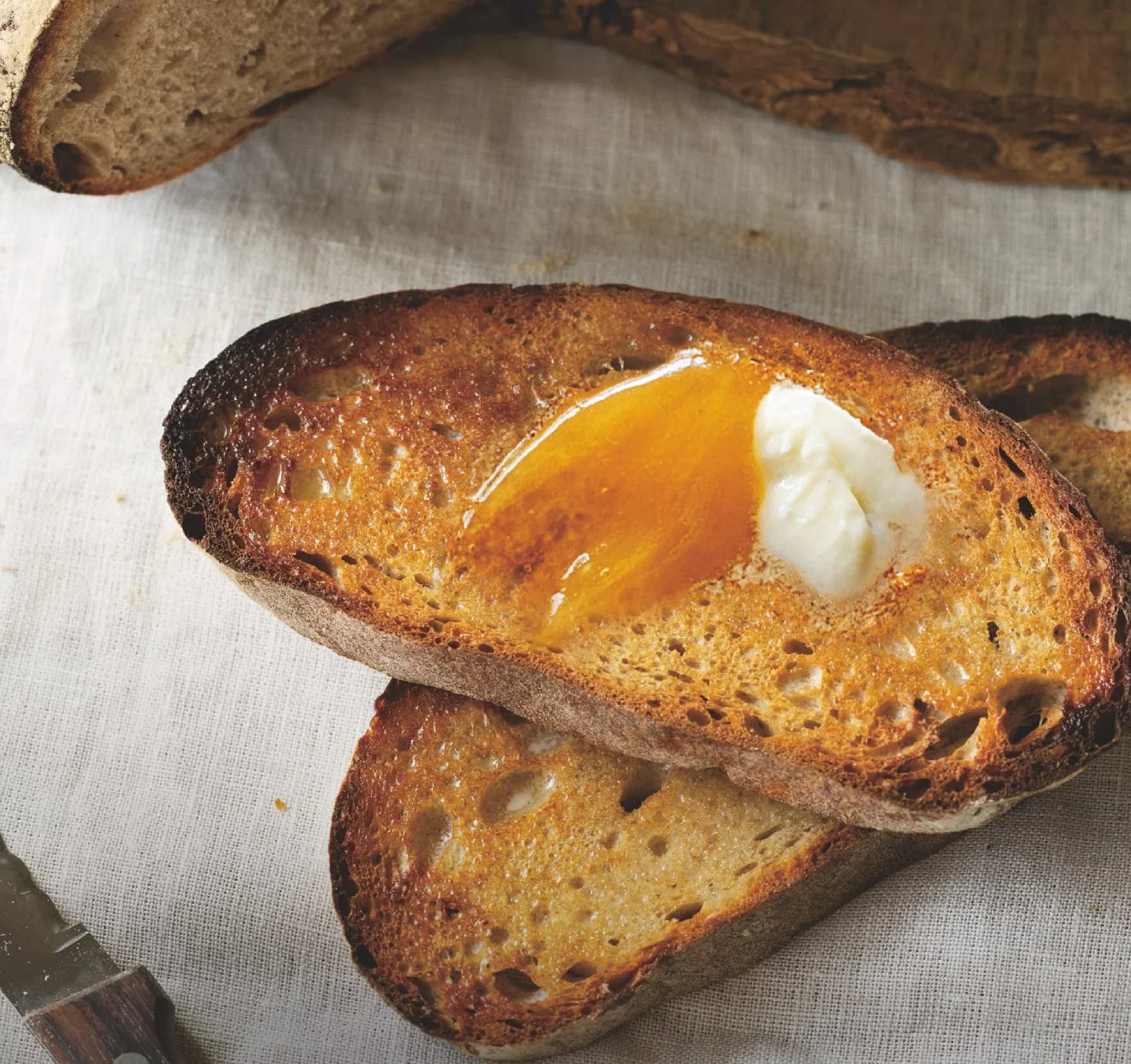 A slice of artisan toast with a glossy layer of honey and a smear of soft butter.